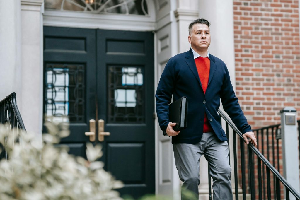 Professional man in stylish attire walking outside a building, displaying confidence.